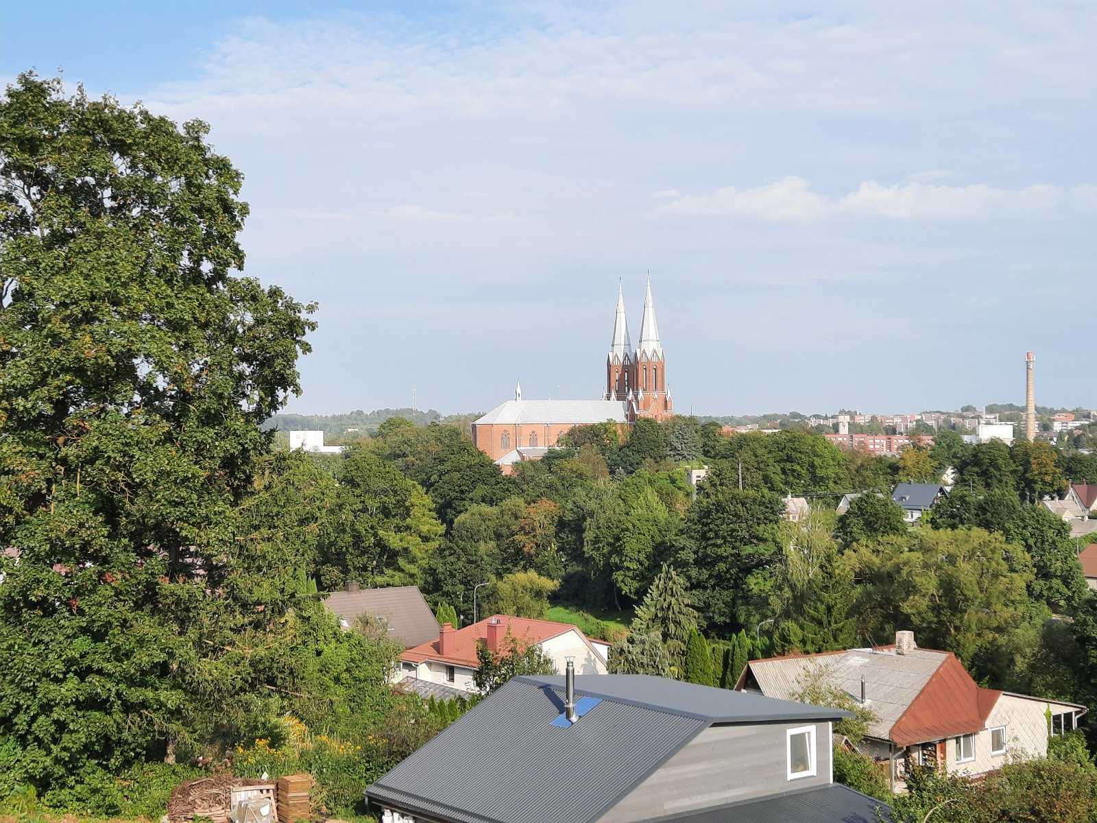 Twin church spires above trees and rooftops in Anykščiai.