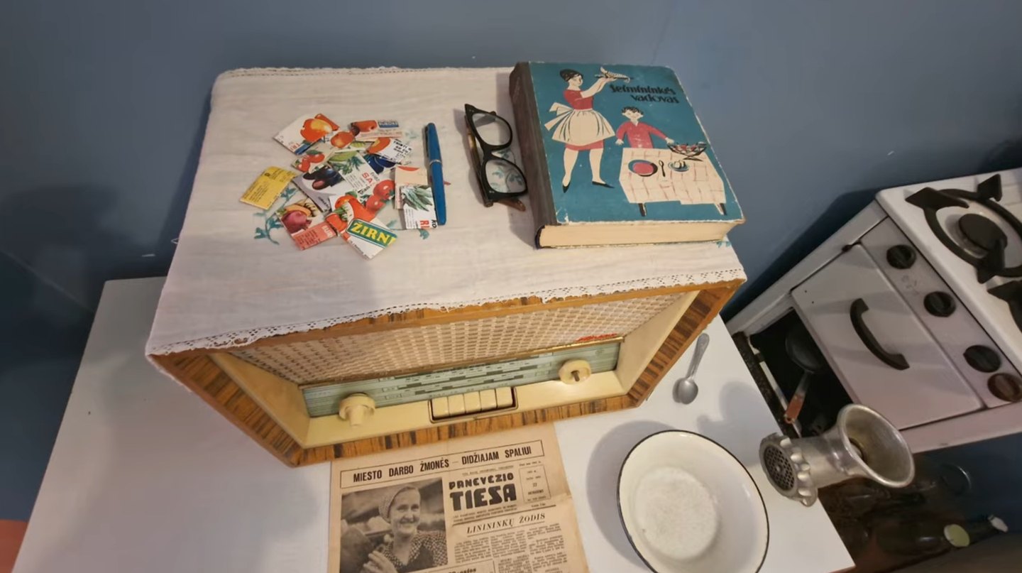 Domestic history display with a vintage radio, cookbook and newspaper at Panevėžys Local Lore Museum