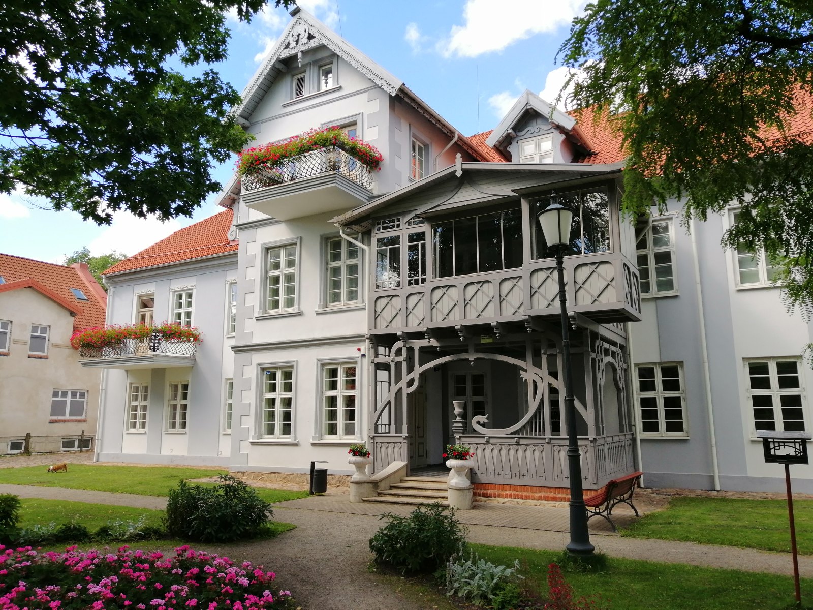 Flower balconies and a wooden veranda at Hugo Scheu Manor in Šilutė.