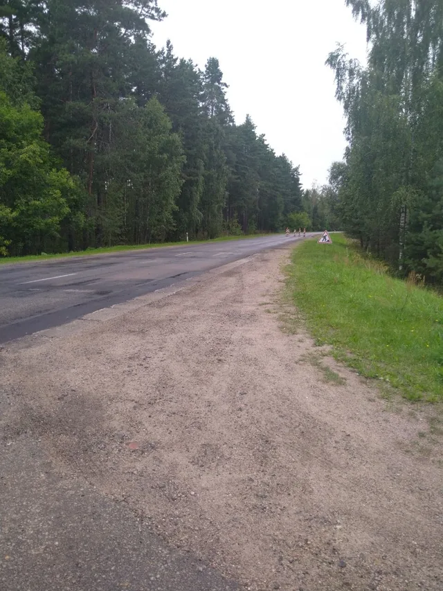 Patched asphalt beside a gravel shoulder and temporary roadworks sign