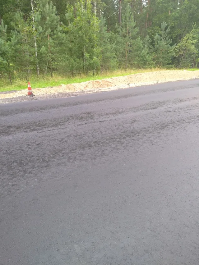 Close view of rough uneven asphalt beside temporary road repair works